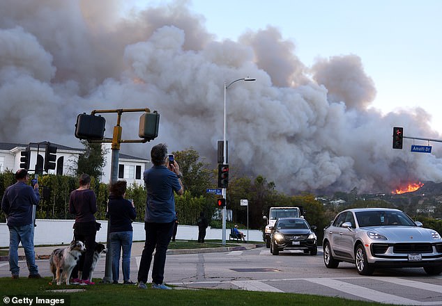 A Porsche is seen driving away from the fiery scene in Los Angeles on Tuesday