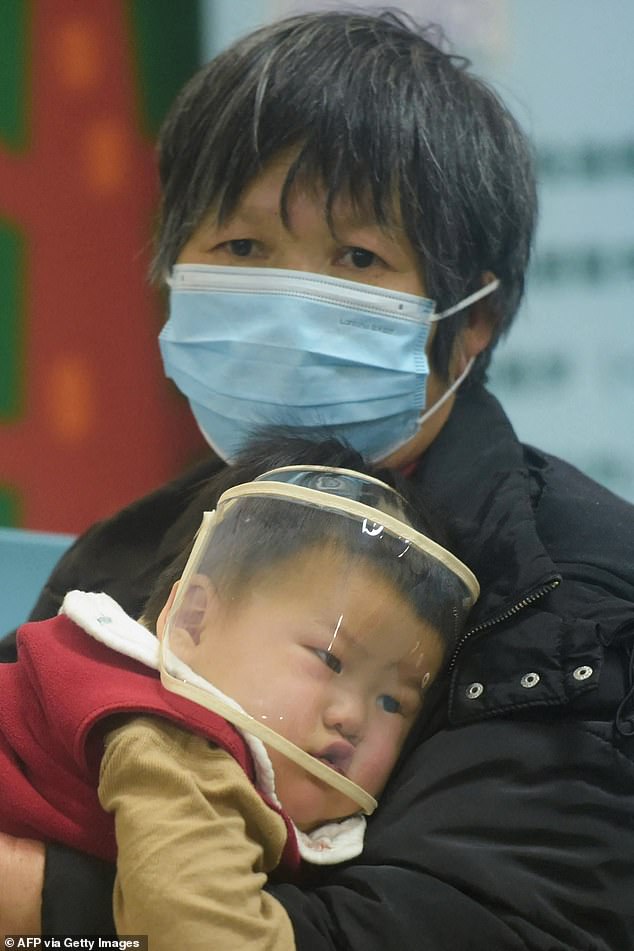 An adult holds a child wearing a face shield as he waits to be treated by medical staff at a hospital in Hangzhou, China.