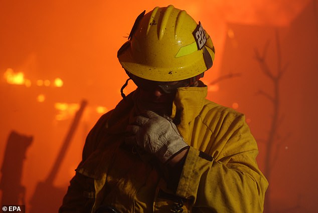 A firefighter tries to cover his face from the thick smoke as he battles the inferno