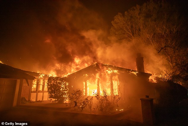 Flames from the Palisades Fire burn a house during a powerful storm on January 8