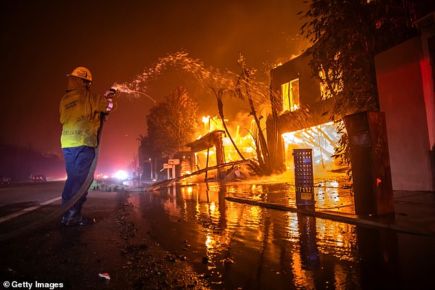 A firefighter battles the Palisades Fire as it burns homes on Pacific Coast Highway amid a powerful wind storm on January 8.