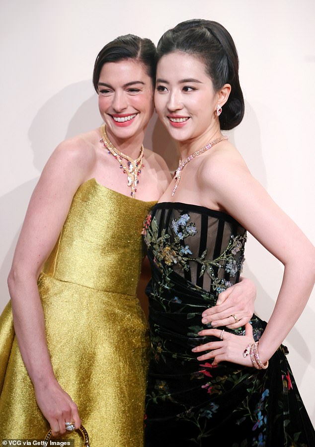 Hathaway put her arm around the 37-year-old Chinese-American woman to bring a smile to her face at the 'Serpenti Infinito' event that coincides with the Year of the Snake, which is supposed to symbolize renewal and prosperity.