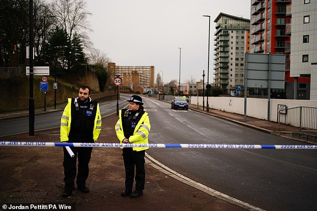 Two police officers stand outside a police cordon on Woolwich Church Road, where the teenager was stabbed to death on Tuesday.