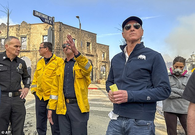 California Governor Gavin Newsom, right, surveys damage in Pacific Palisades with CalFire's Nick Schuler during the Palisades Fire on Wednesday