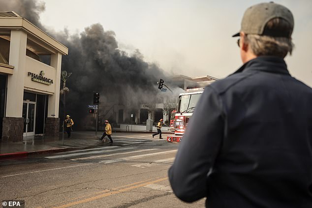 California Governor Gavin Newsom (R) watches as firefighters battle the Palisades Wildfire in the Pacific Palisades neighborhood of Los Angeles