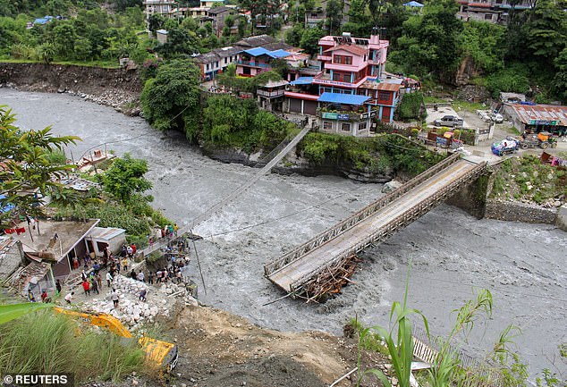 People gather at a bridge damaged by the flood on the Raghu Ganga River in Myagdi, Nepal, July 11, 2020