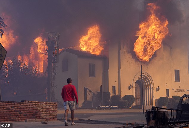 A man walks past the burning Altadena Community Church, Wednesday, Jan. 8, 2025, in Pasadena, California.