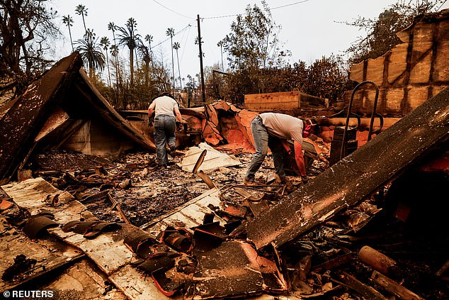 People are seen searching the remains of a house that was burned down in Altadena.