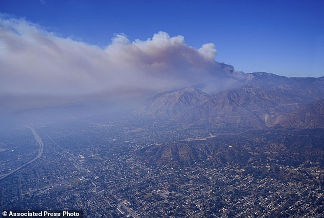 A plume of smoke from a wildfire forms over the Los Angeles city watershed on Thursday