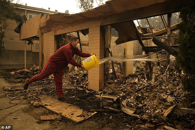 A man extinguishes the fires with water after his house was set on fire