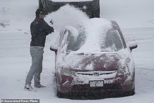 A person dusts snow off a car during a winter storm in Cincinnati on Sunday. (AP Photo/Joshua A. Bickel)