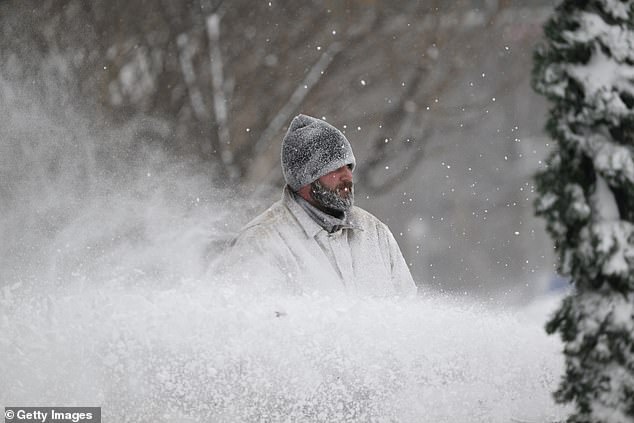 The colossal storm comes just days after several other regions in the US were rocked by heavy snowfall. Pictured: An East Coast resident clearing snow from flooded sidewalks