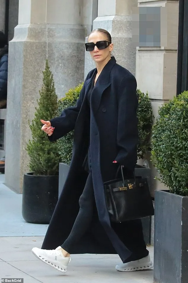 Jennifer Lopez looked effortlessly chic in a long black coat as she stepped out of her 6,540-square-foot penthouse, which she has been listing and delisting since 2017.